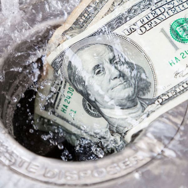 $100 bills disappearing into a garbage disposal with water flowing over them