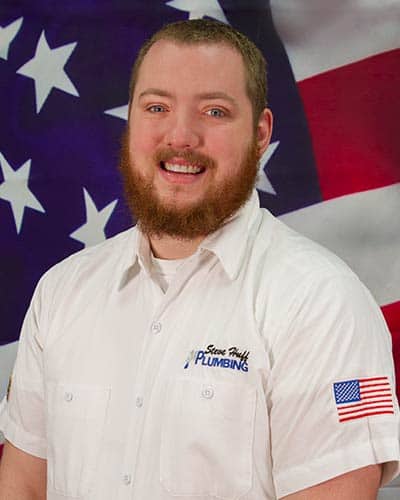 plumber named Jonathan wearing a white shirt sitting in front of American flag