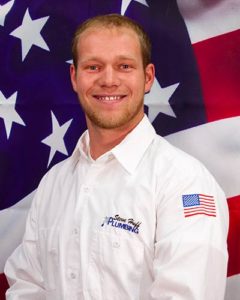 plumber named William wearing white shirt sitting in front of American flag background