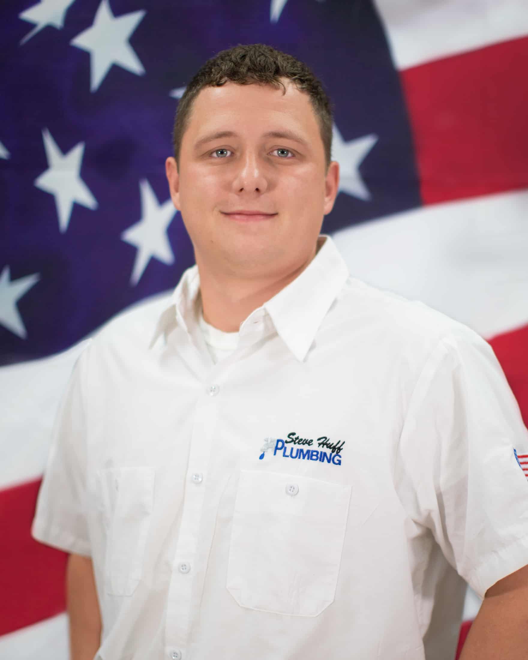 plumber in white shirt sitting in front of American flag