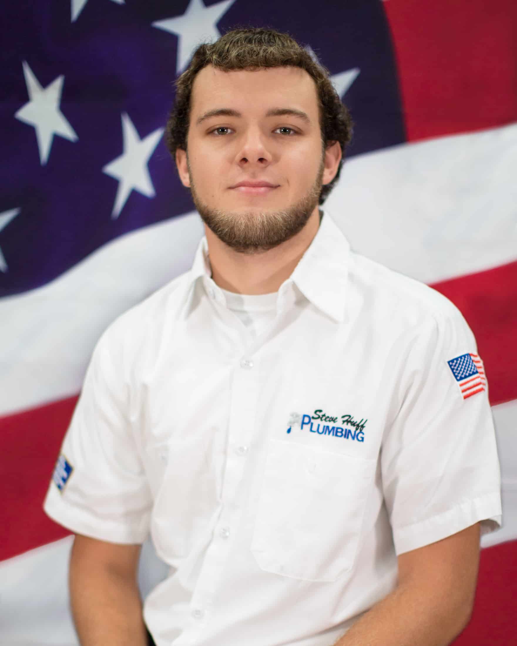 plumber in white shirt sitting in front of American flag